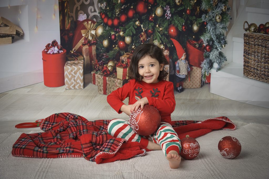 Bambina che scarta i regali durante servizio fotografico di Natale